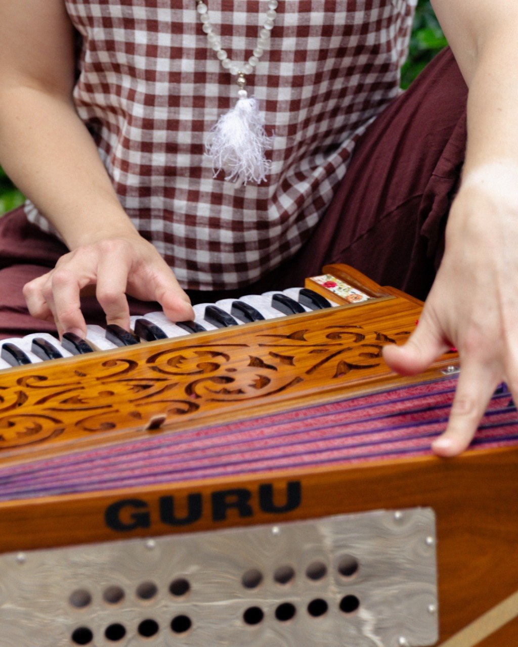 Hands gently playing the harmonium keys during sound practice
